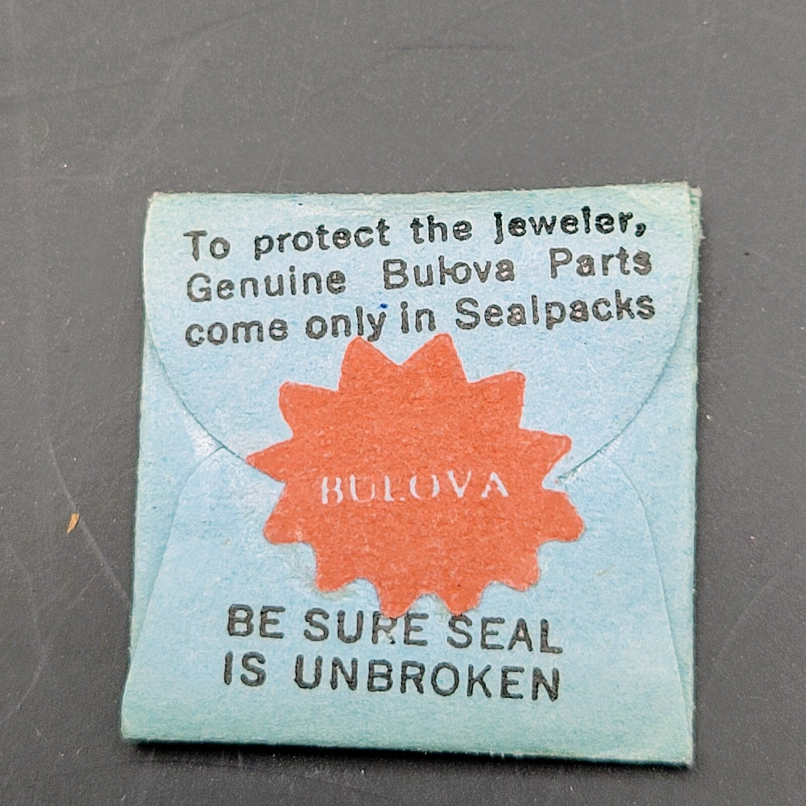 Vintage Bulova watch parts packaging with text on a gray background