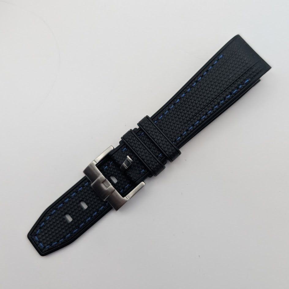 Black textured watch strap with silver buckle on a light gray background