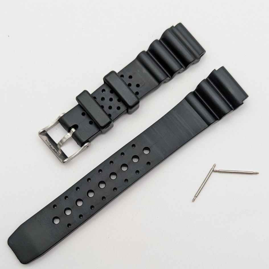 Black watch strap with holes and a metal buckle on a light gray background